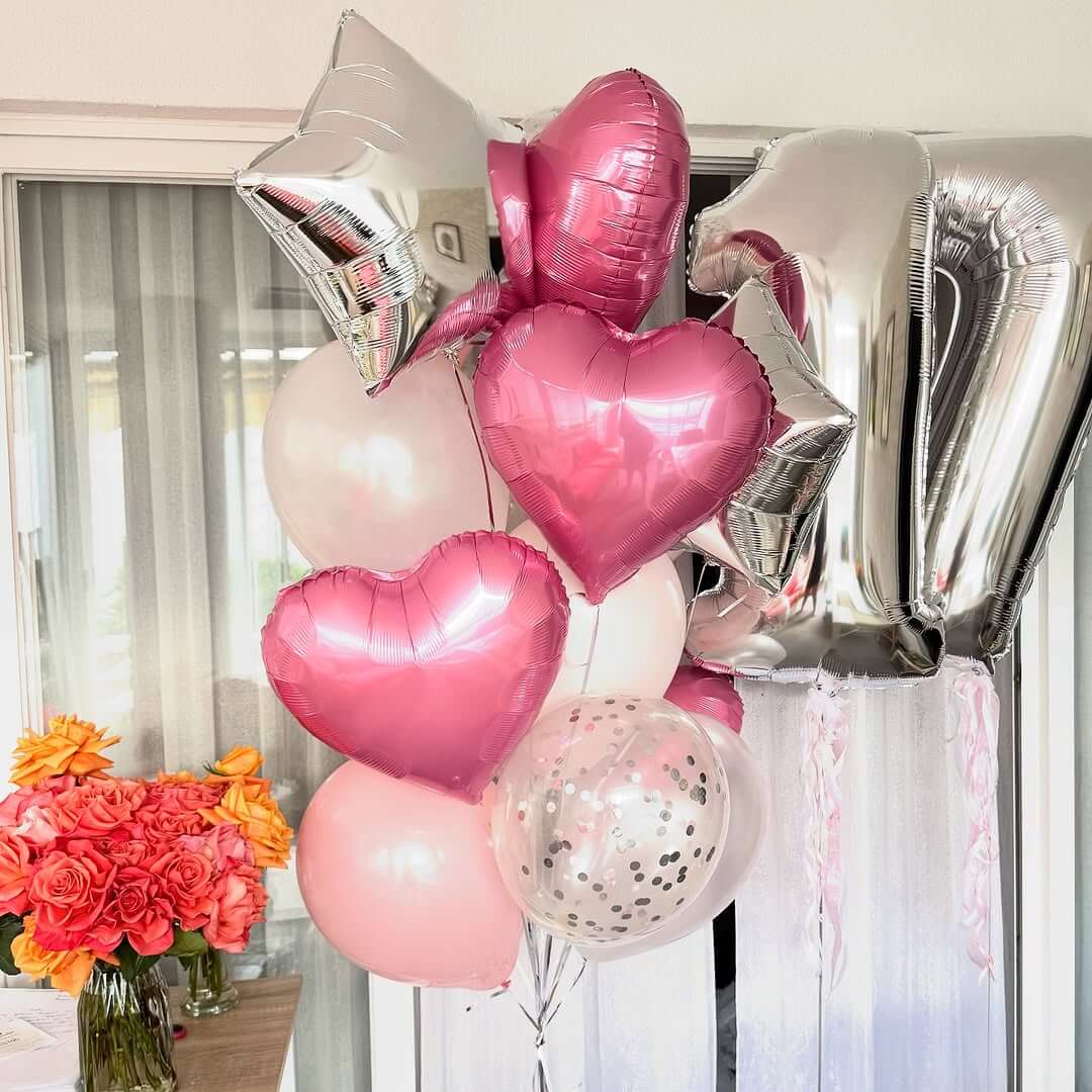 Decorative balloons including heart-shaped and number balloons with a bouquet of flowers in the foreground.