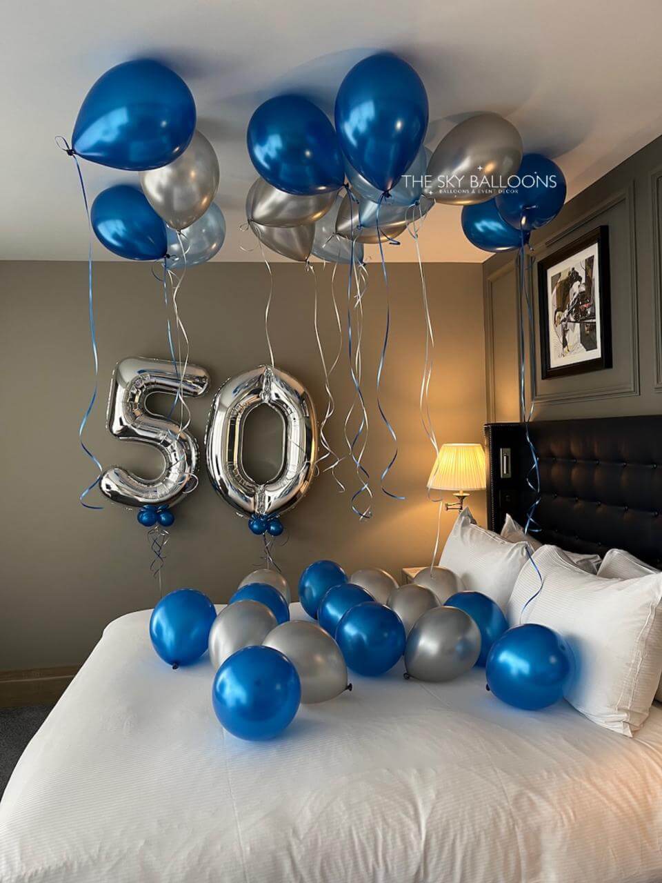 Decorative balloons with '50' on a bed in a bedroom setting.