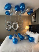 Decorative balloons with '50' on a bed in a bedroom setting.