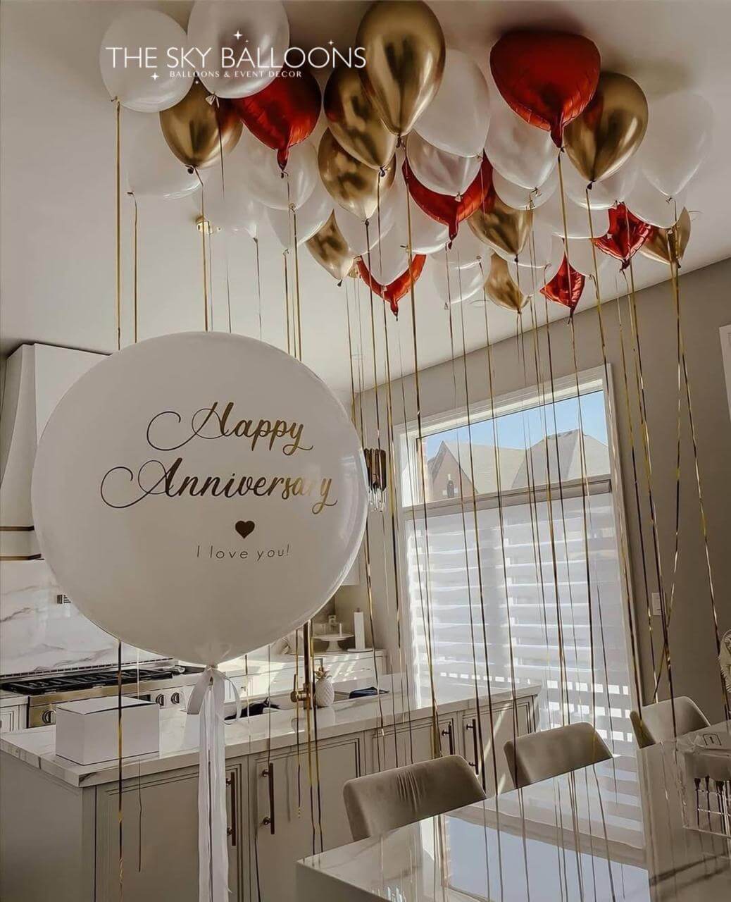 Decorative balloons with 'Happy Anniversary I love you' sign in a kitchen.
