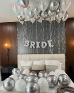 Decorative setup with balloons and 'BRIDE' letter balloons in a bedroom.