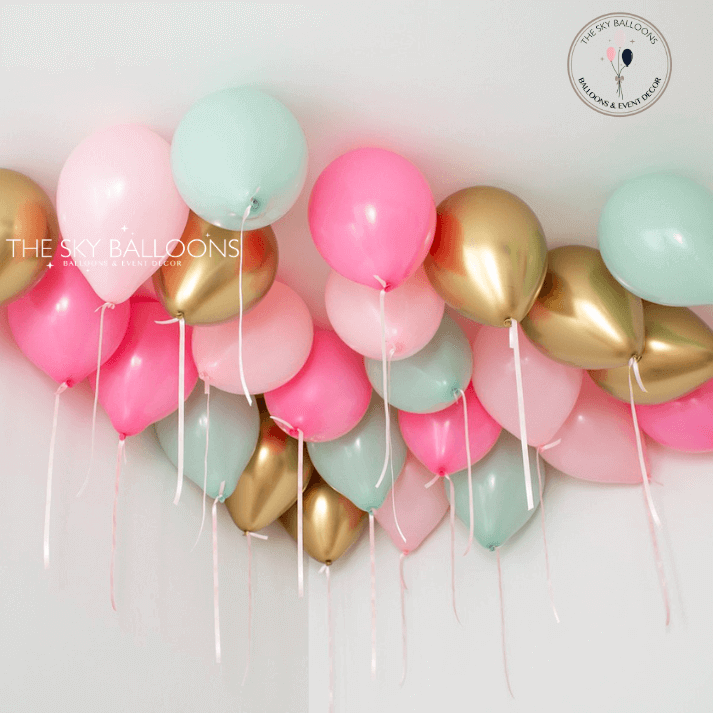 A cluster of helium-filled balloons in pink, gold, and mint green colors, arranged for ceiling decoration.