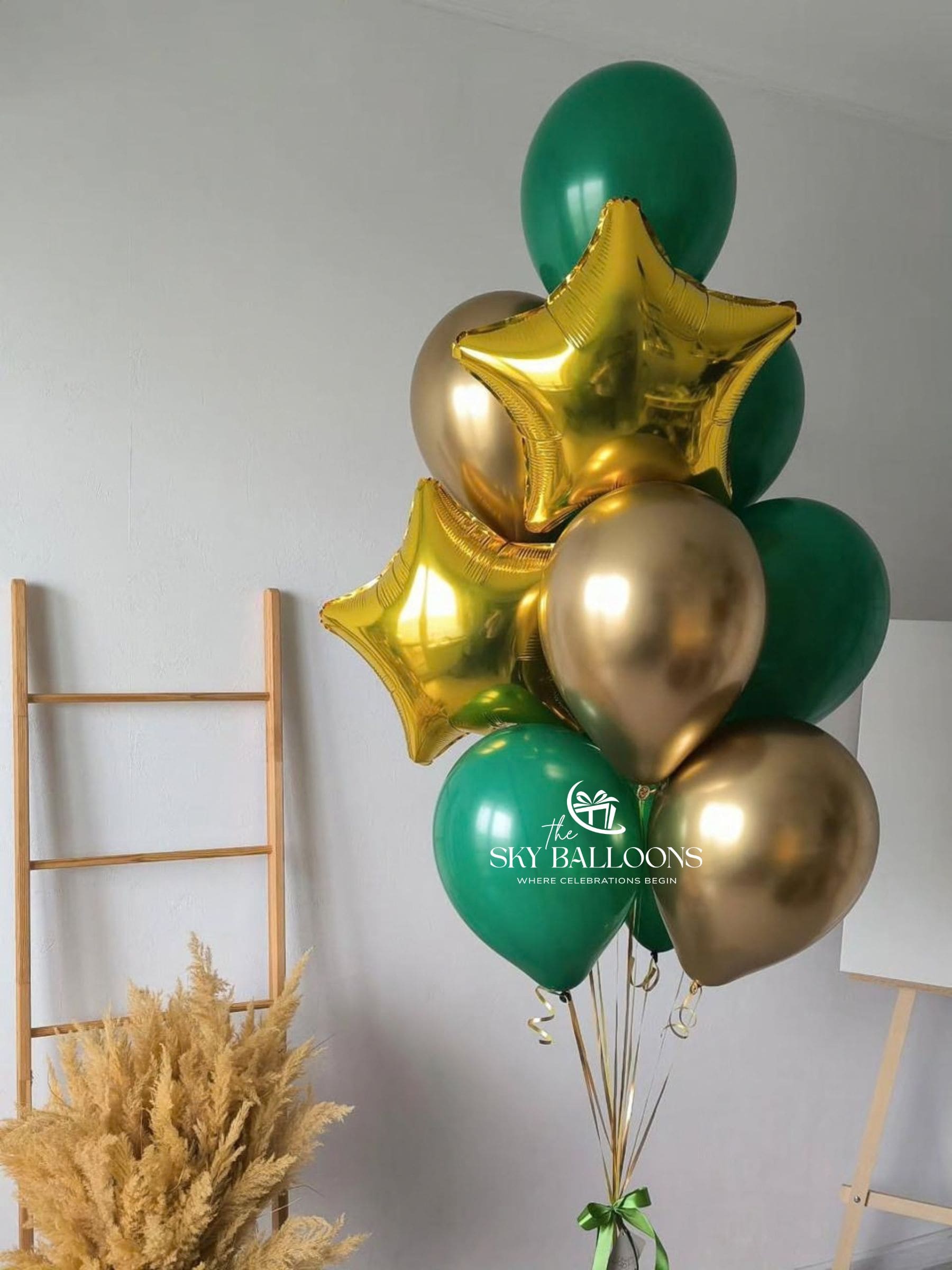 Forest-green and chrome-gold latex balloon bouquet with two gold star foil balloons and coordinating curling ribbons.