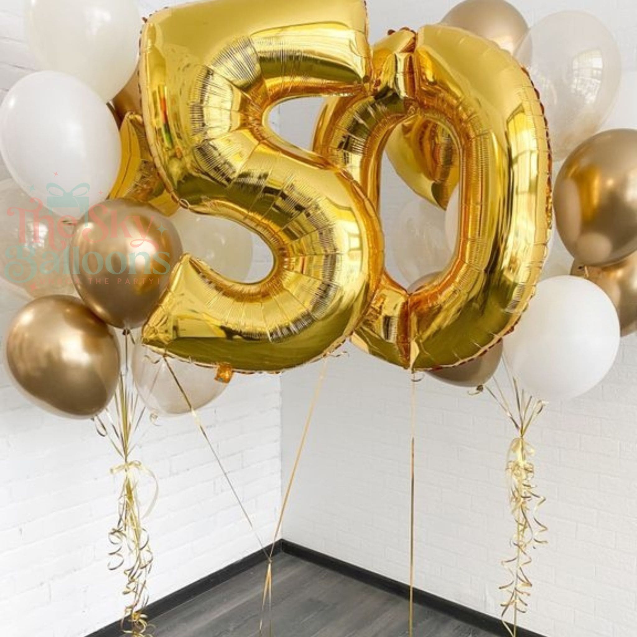 Gold '50' balloons with white and gold streamers on a plain background