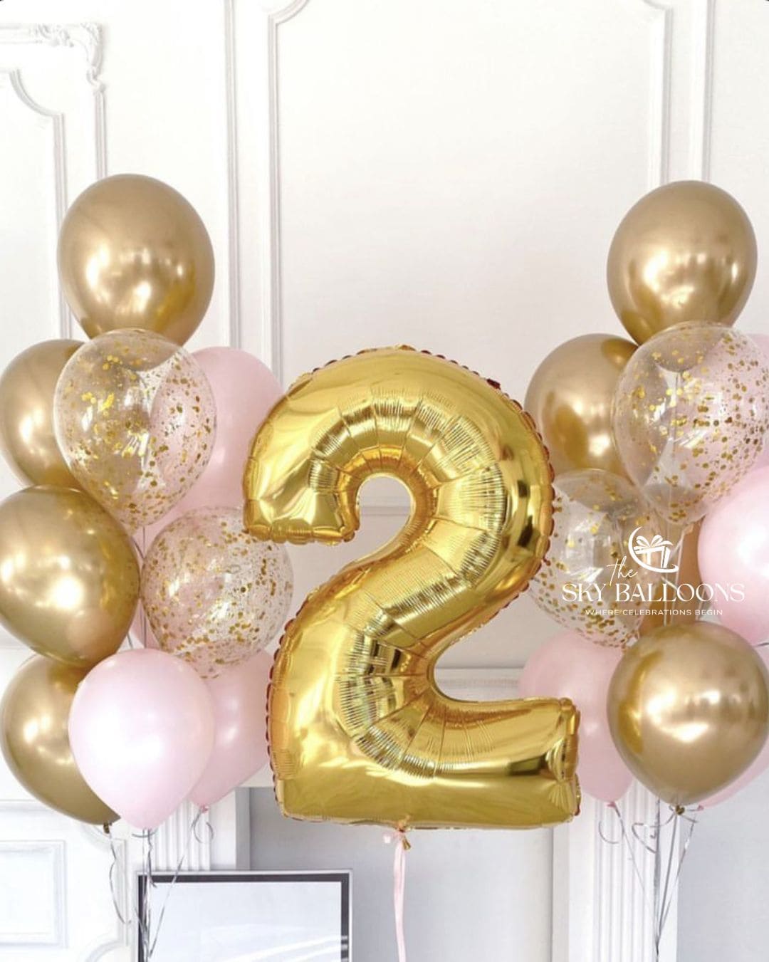 Gold number 2 foil balloon between bunches of blush-pink, chrome-gold and clear gold-confetti latex balloons.