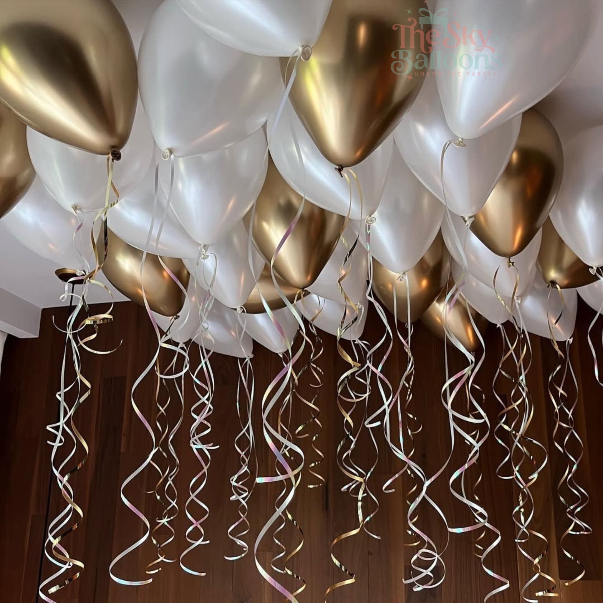 Gold and white balloons with streamers against a dark background