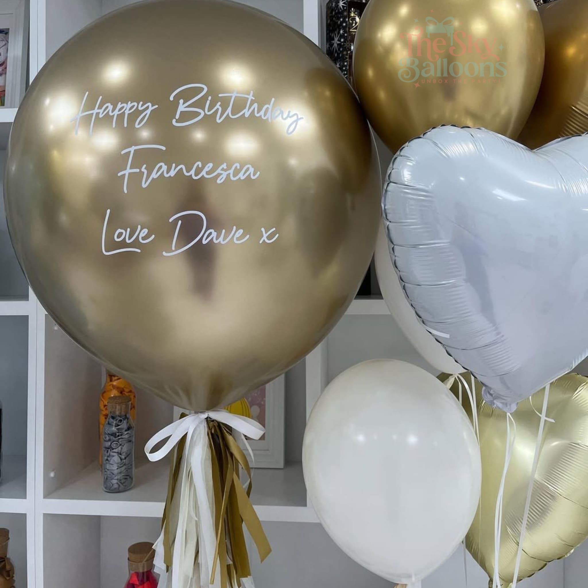 Gold balloon with personalized message and other balloons in the background