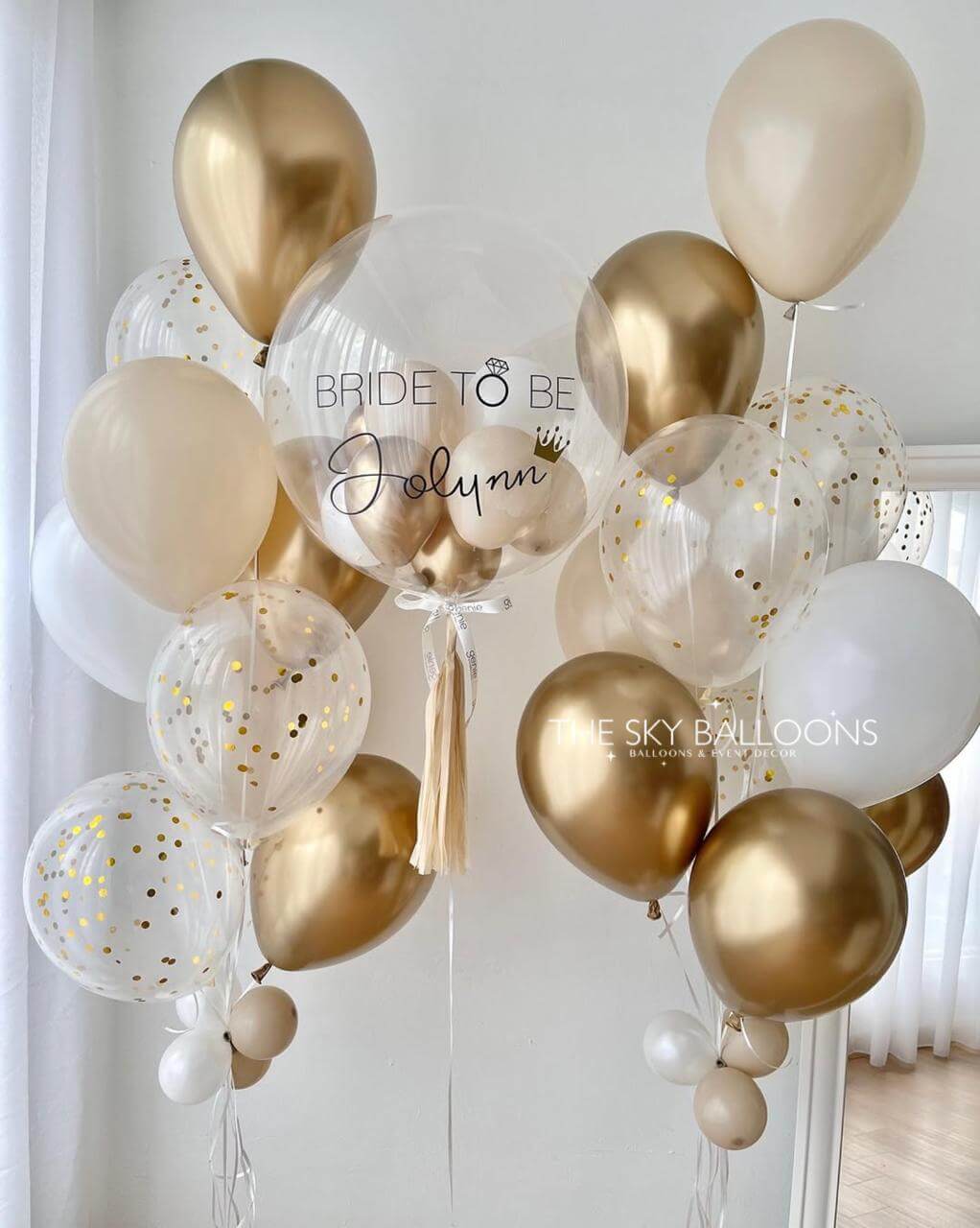 Gold, white, and clear balloons with 'Bride to Be' text against a light background