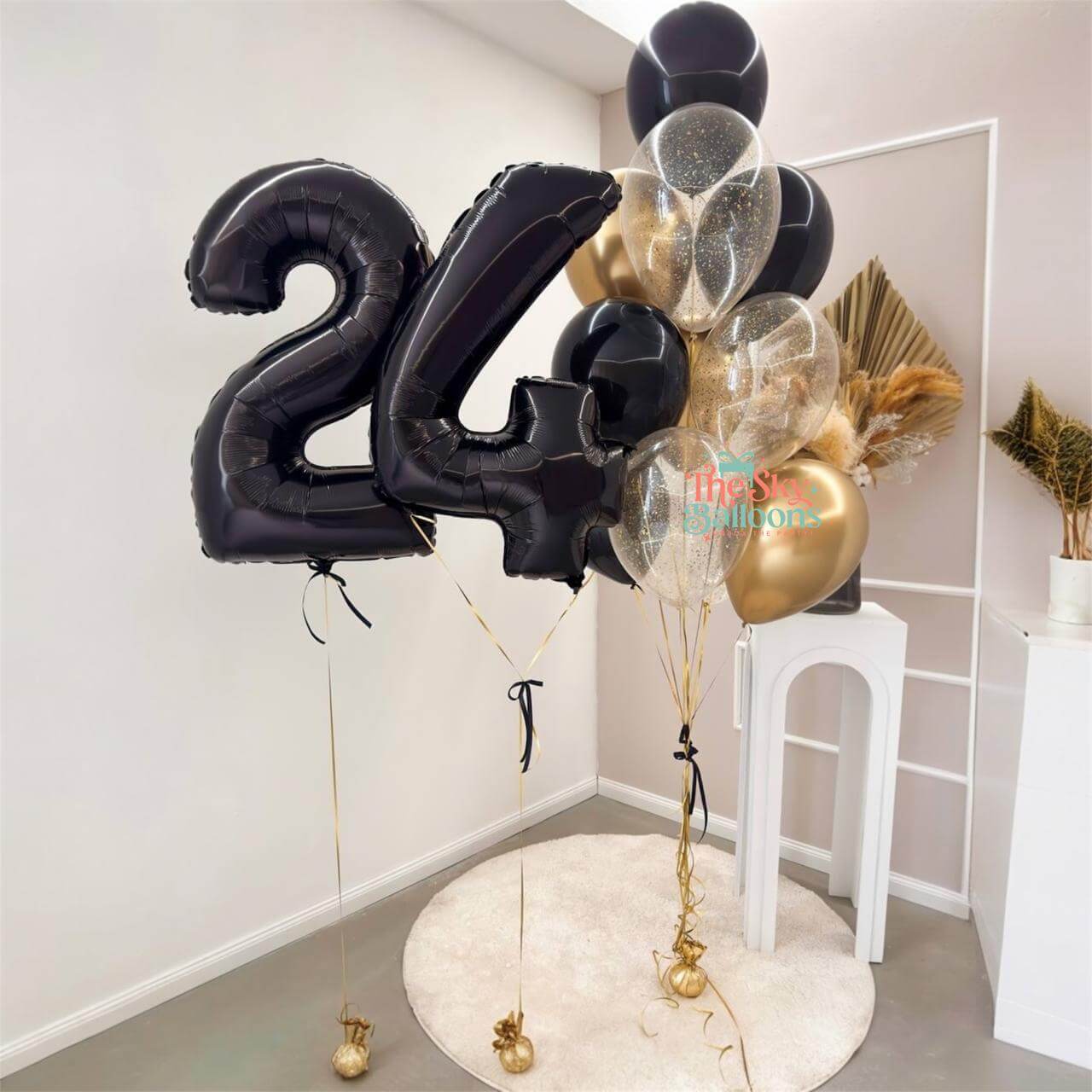 Black number '24' balloon and decorative balloons in a room setting.