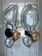 Silver number '40' balloons with smaller gold, black, and silver balloons against a white door background.