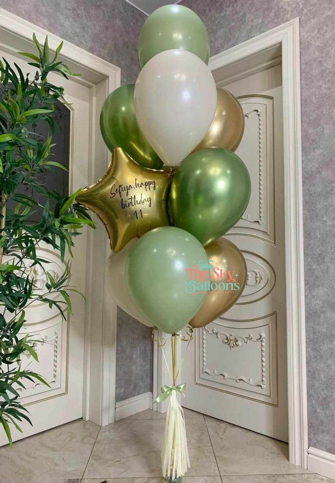 Decorative balloons with text in a room with a plant and door.