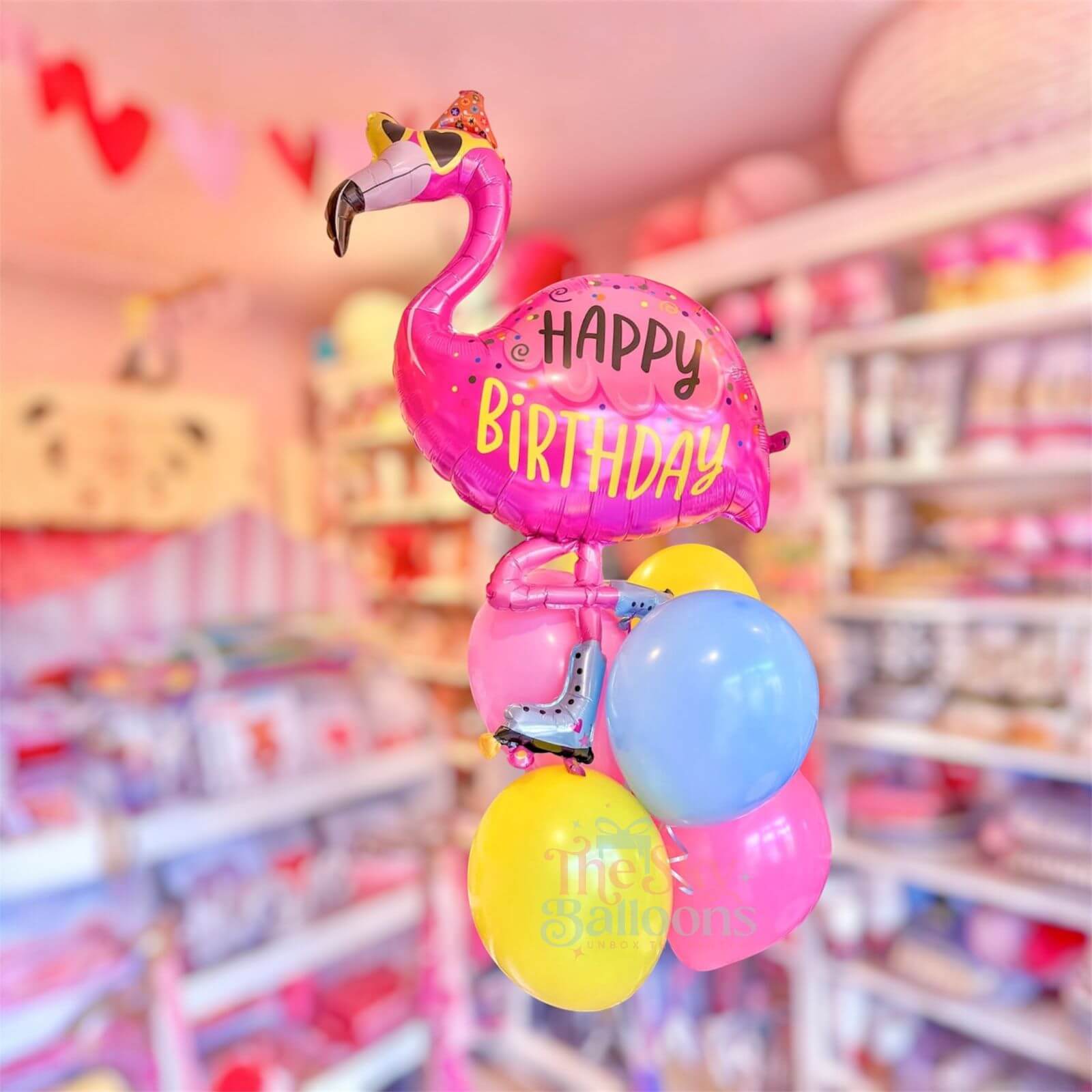 Flamingo-shaped 'Happy Birthday' balloon with colorful balloons in a store setting