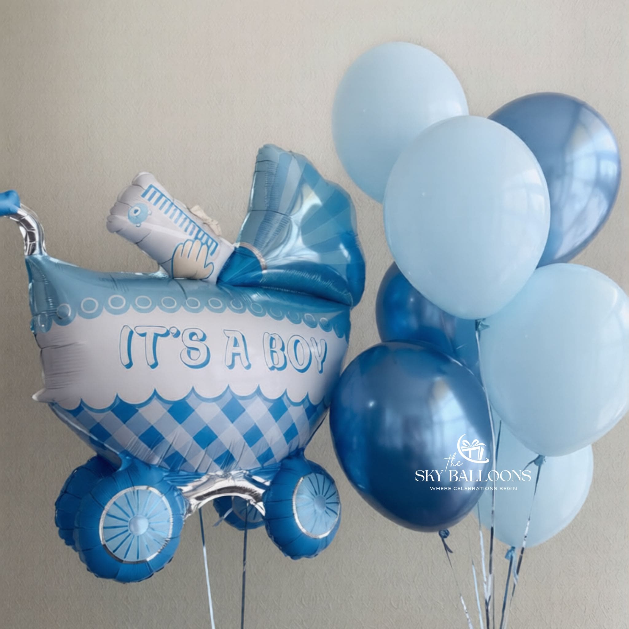 Blue baby buggy foil balloon reading “It’s a Boy,” alongside a bouquet of pastel blue and metallic blue latex balloons.
