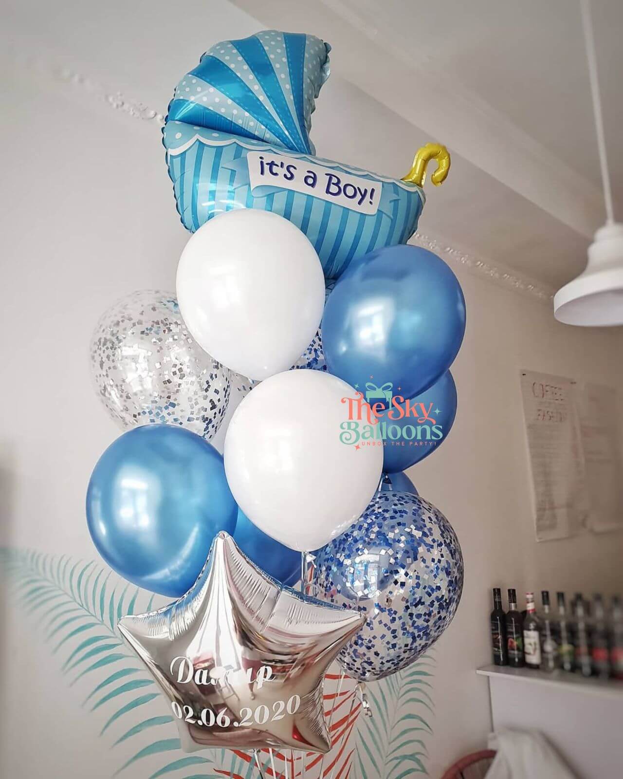 Balloon arrangement with 'it's a boy!' message and personalized details in a room setting.
