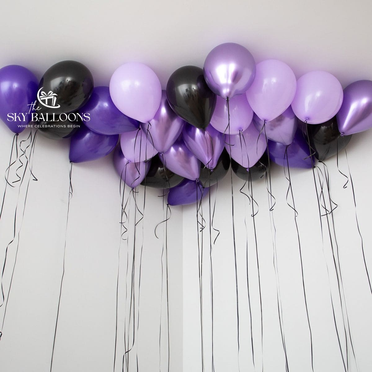 Purple, lilac, metallic-purple and black helium ceiling balloons with long hanging black ribbons.