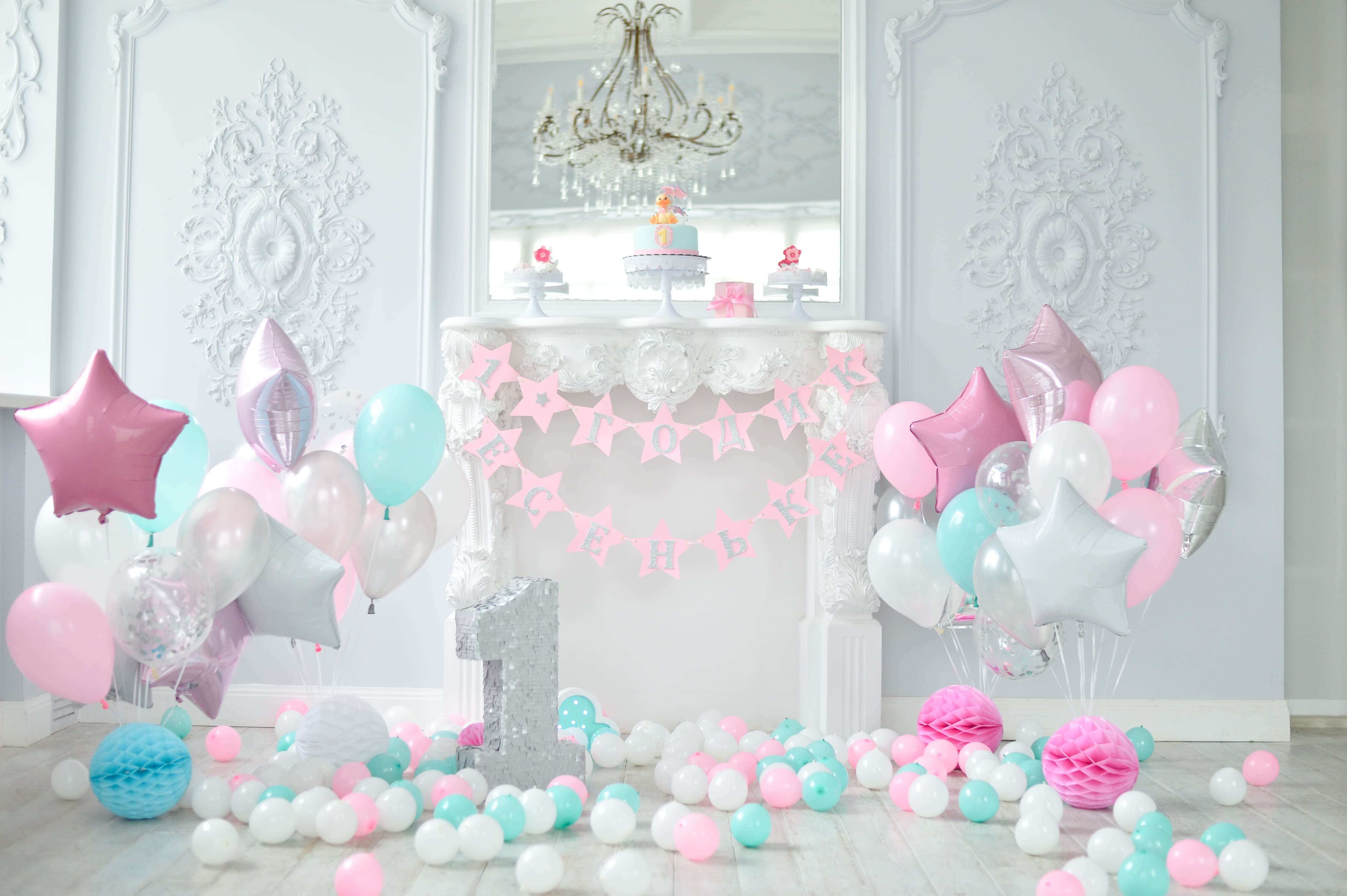 Pastel-themed first birthday decor with pink, mint, and silver balloons, a banner, and a large number one piñata.