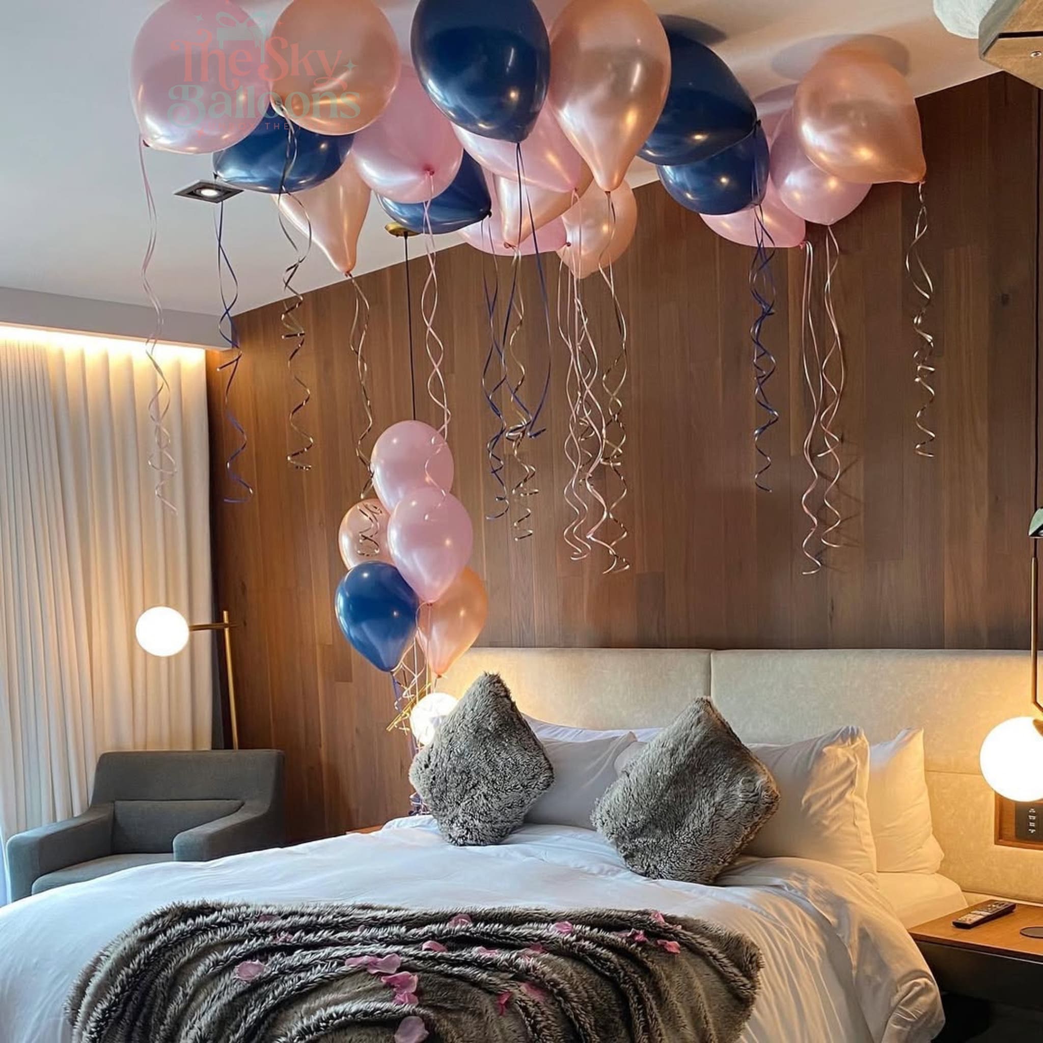 Decorative balloons above a bed in a room with a wooden wall.