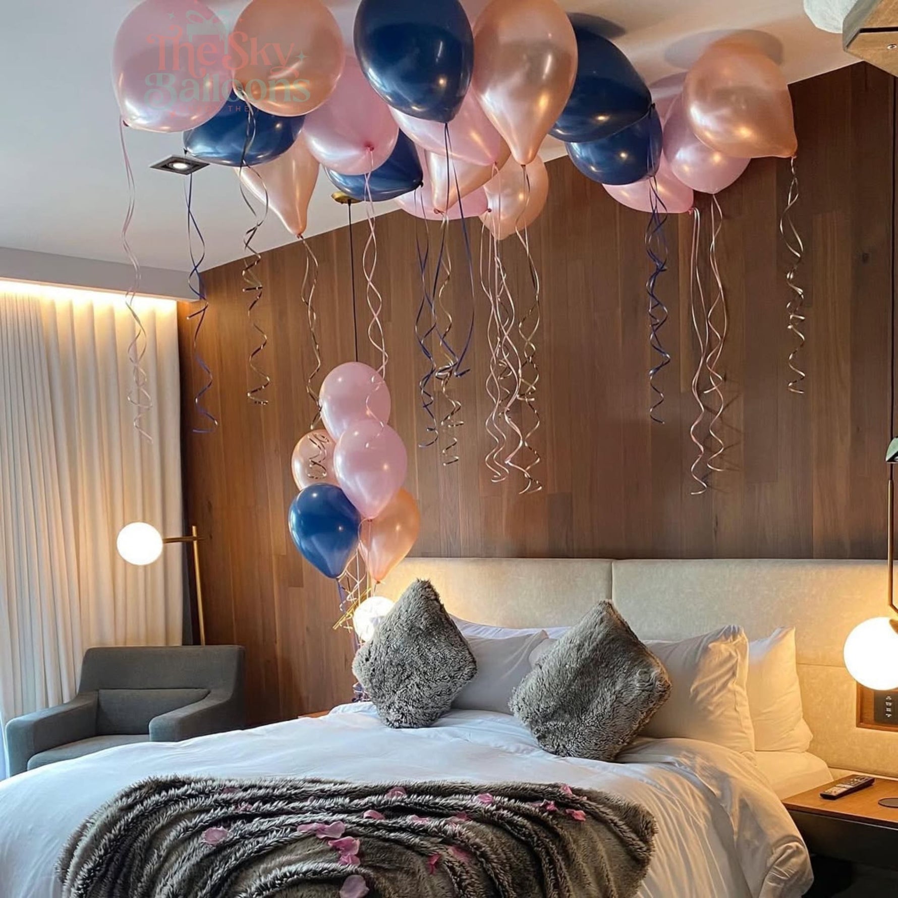 Decorative balloons above a bed in a room with a wooden wall.
