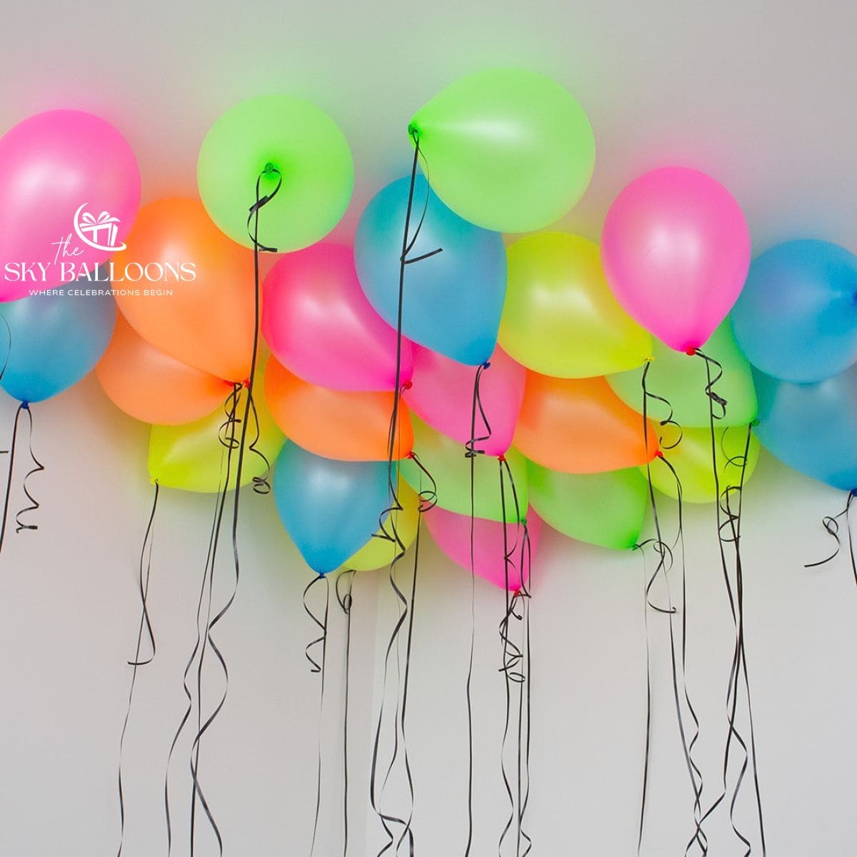 Neon pink, green, yellow, orange and blue helium ceiling balloons with hanging black curling ribbons.