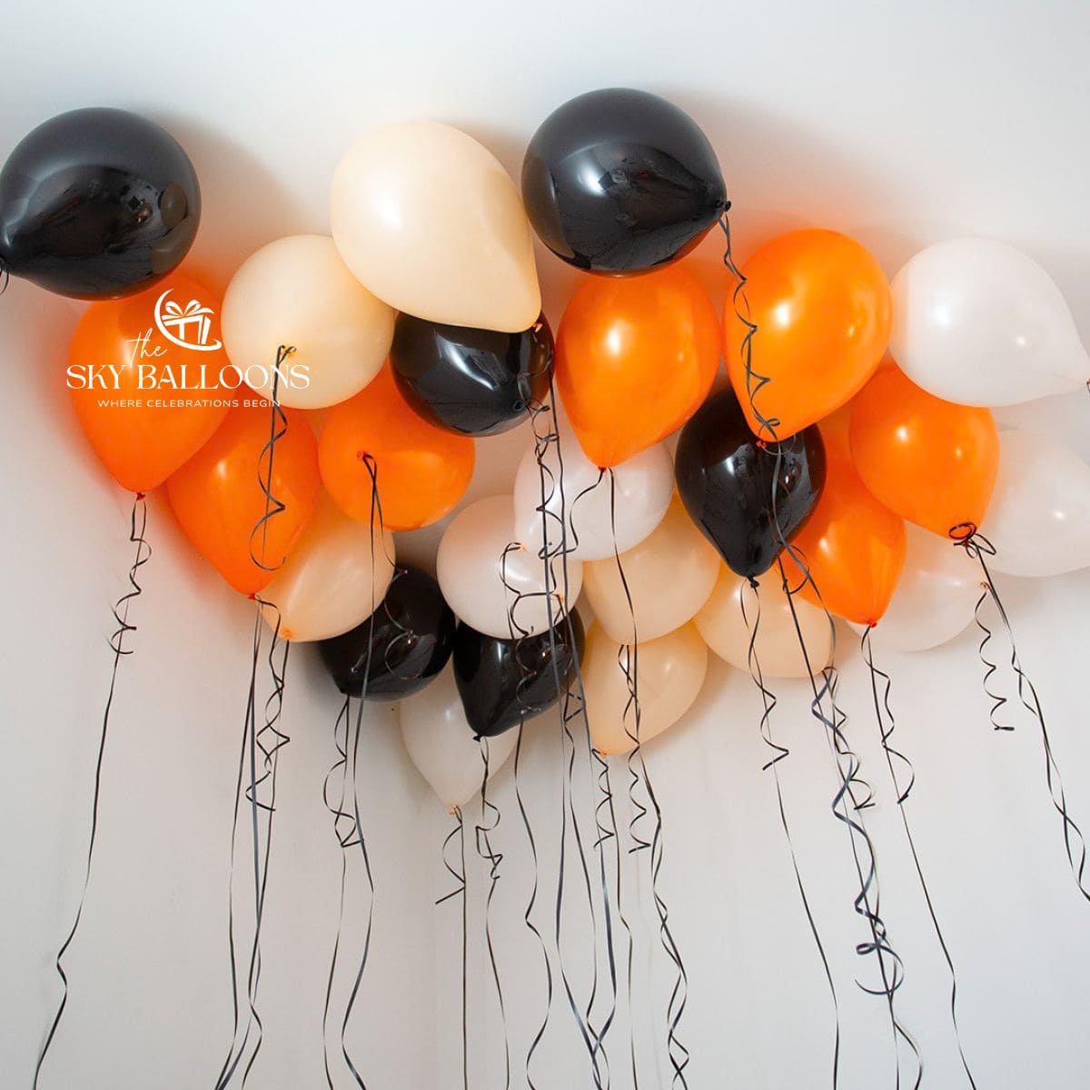 Orange, black, cream and white helium ceiling balloons with hanging black curling ribbons.