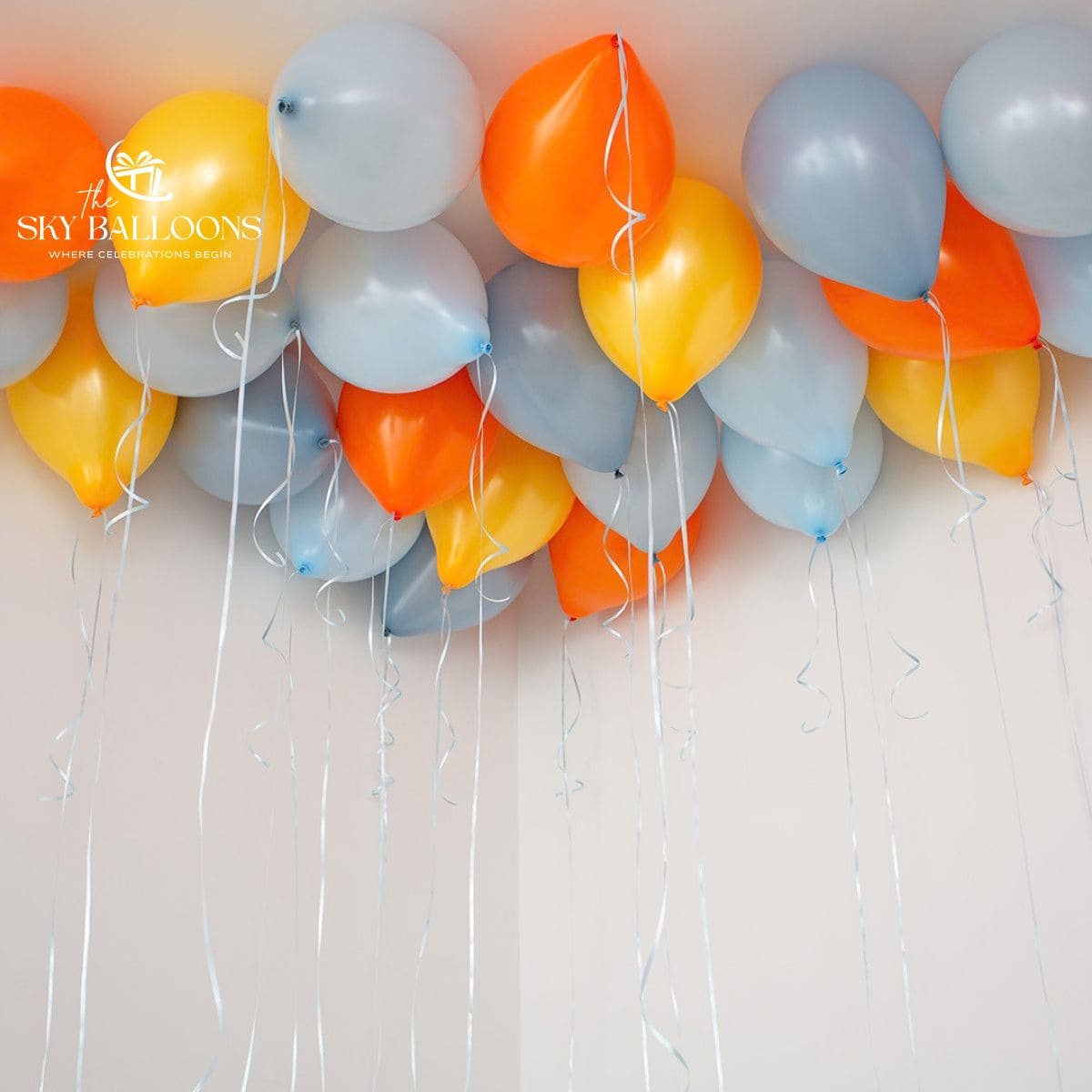 Orange, yellow and pale-blue helium ceiling balloons with long white curling ribbons.