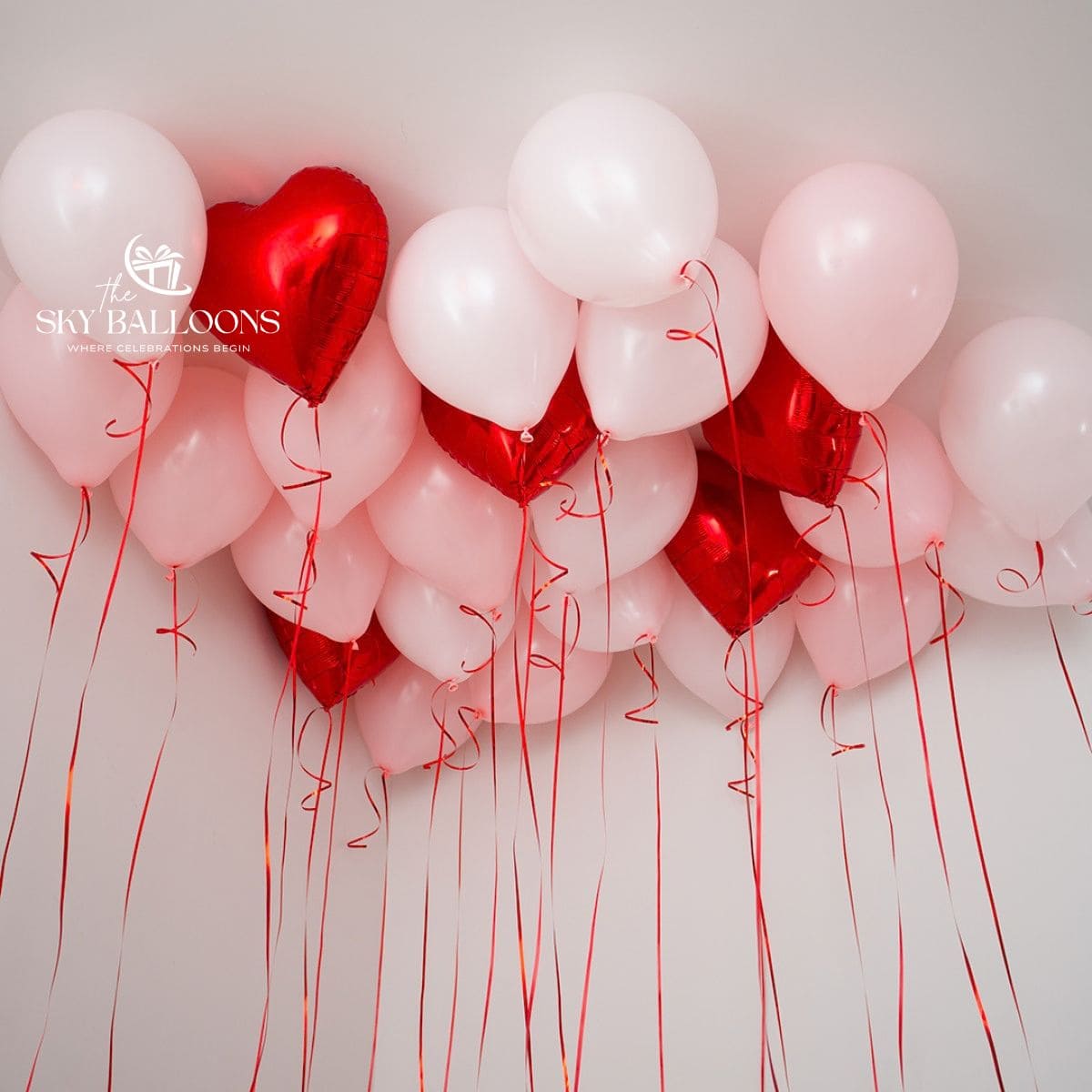 White helium ceiling balloons mixed with red heart foil balloons and hanging red curling ribbons.