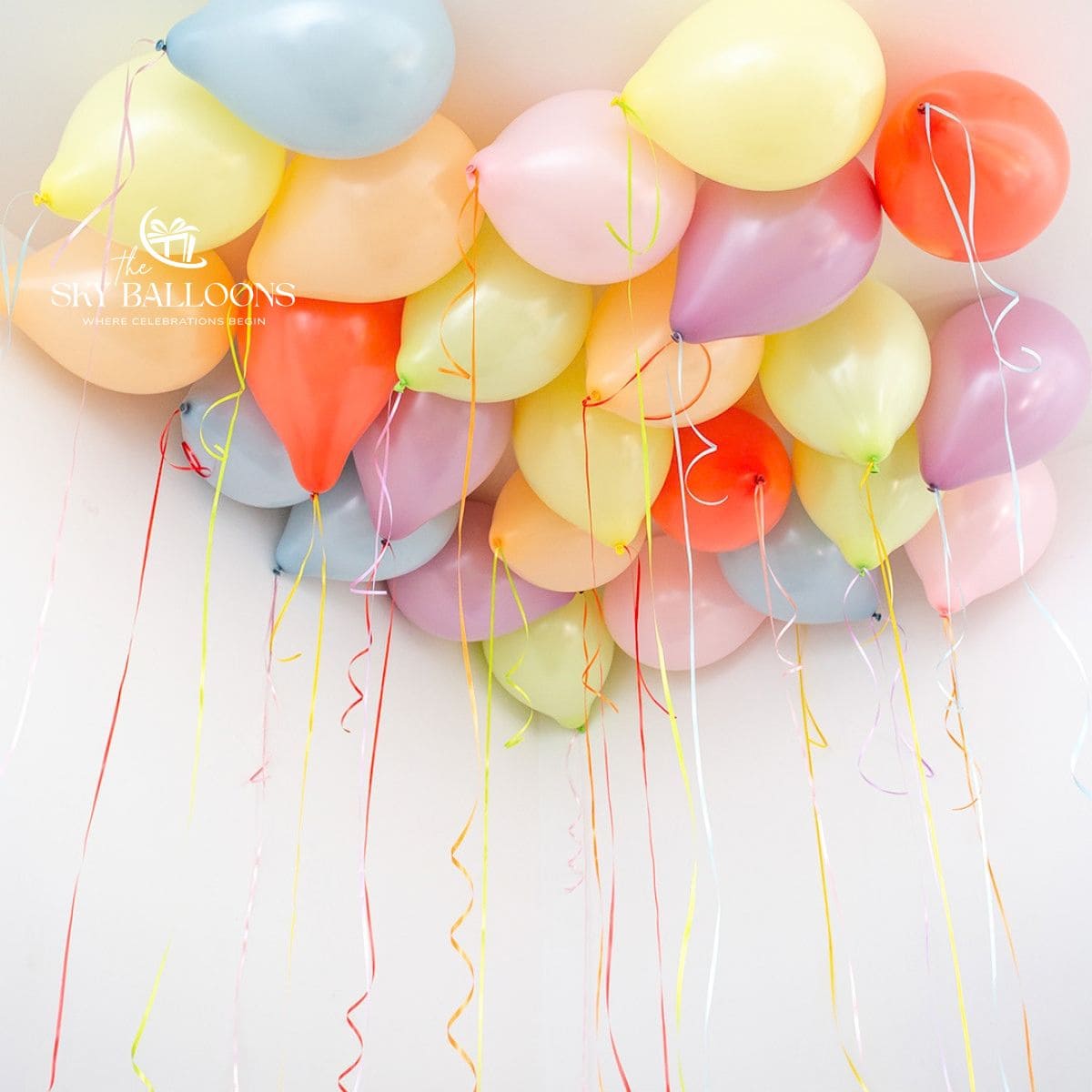 Pastel yellow, baby-blue, lilac, pink, peach and coral helium ceiling balloons with multicoloured curling ribbons.