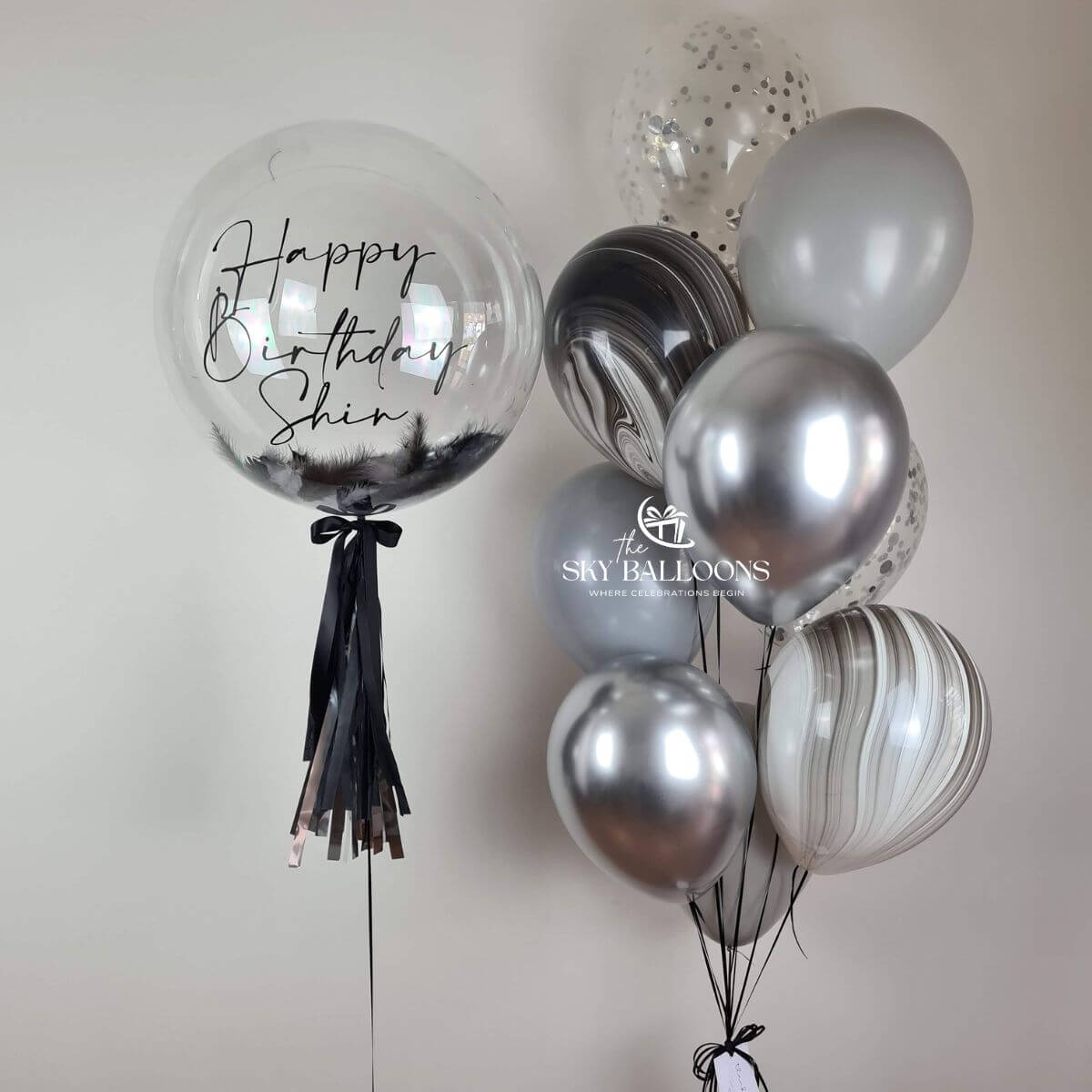 A shiny silver and black balloon with "Happy Birthday" printed on it, adding celebration vibes.