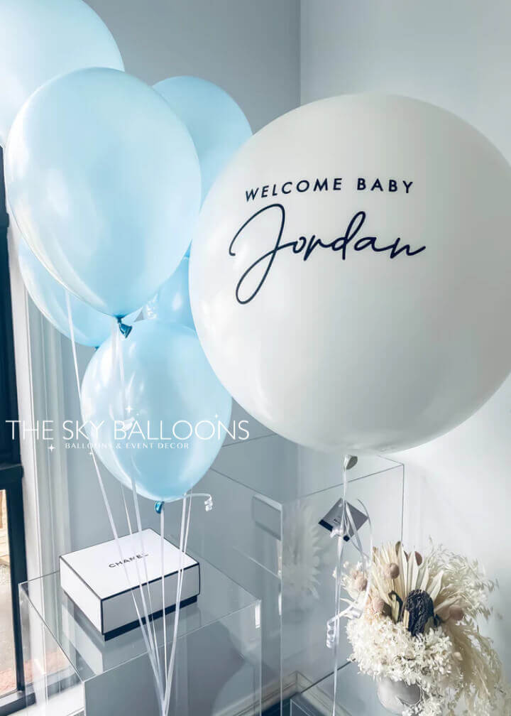 Customized 24-inch helium-filled New Born Baby balloon in pastel blue with smaller decorative balloons, perfect for welcoming a newborn
