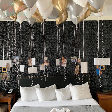 Decorative setup with balloons and photo streamers on a bed in a room.