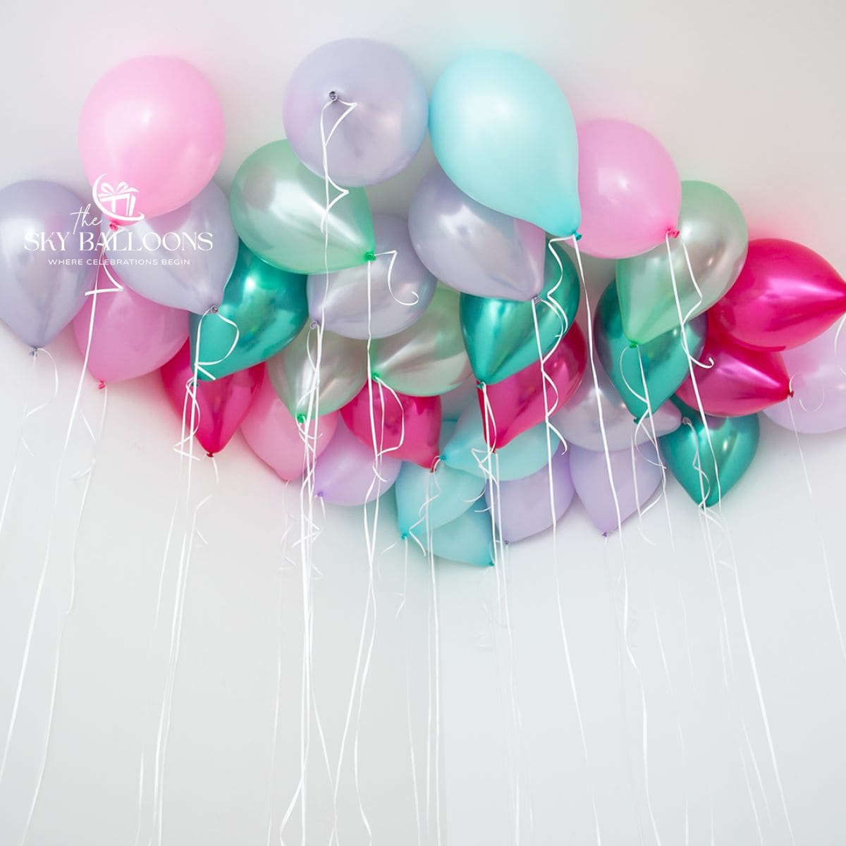 Pink, lilac, mint and teal helium ceiling balloons with metallic fuchsia and teal accents and hanging white ribbons.