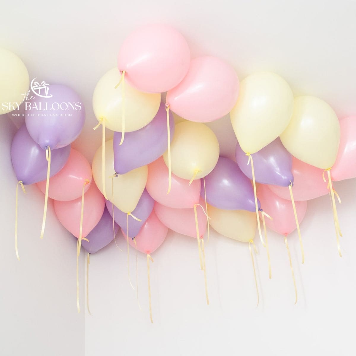Pastel pink, lilac and pale-yellow helium ceiling balloons with hanging yellow ribbons.