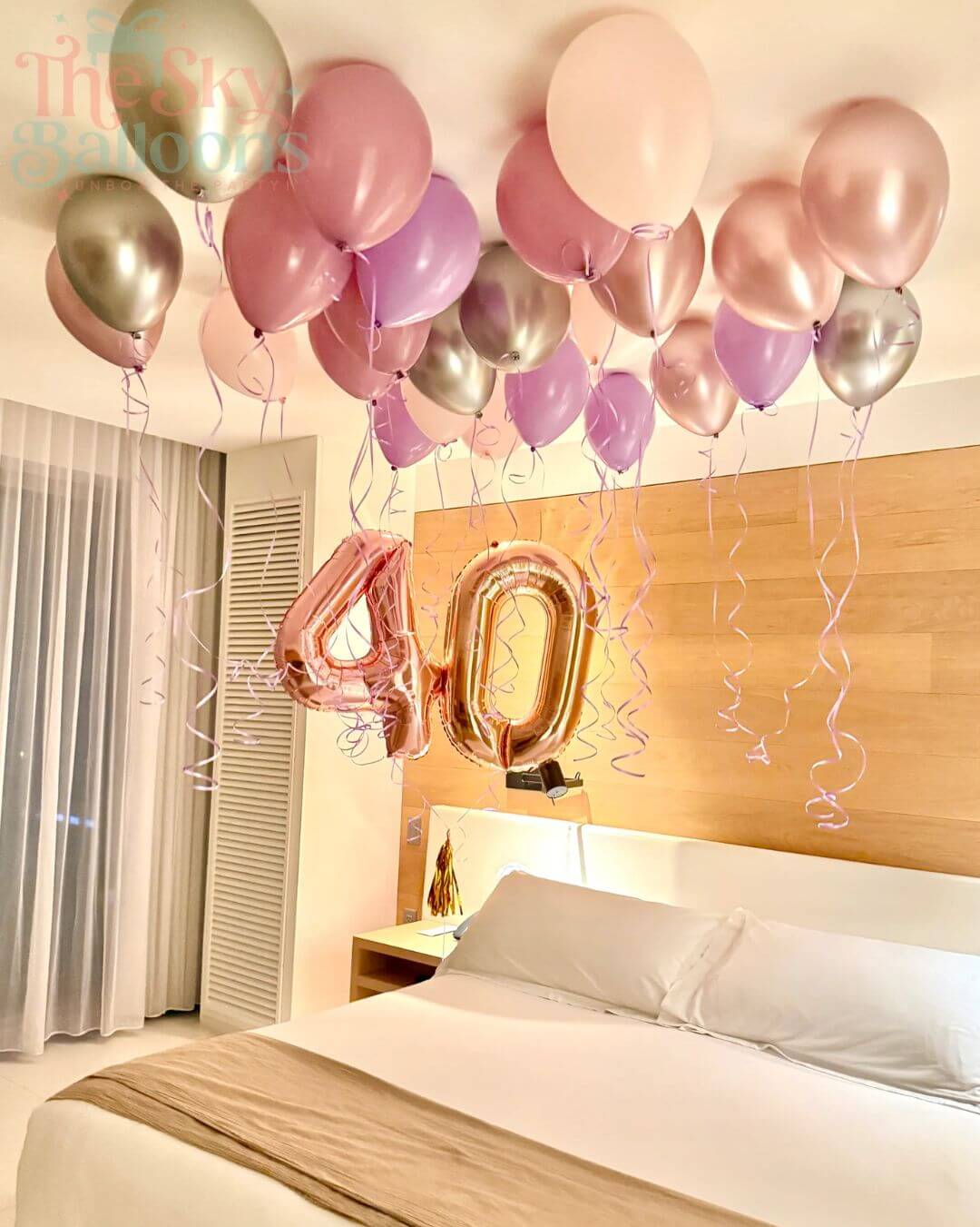 Decorative balloons with a '40' foil balloon in a bedroom setting.