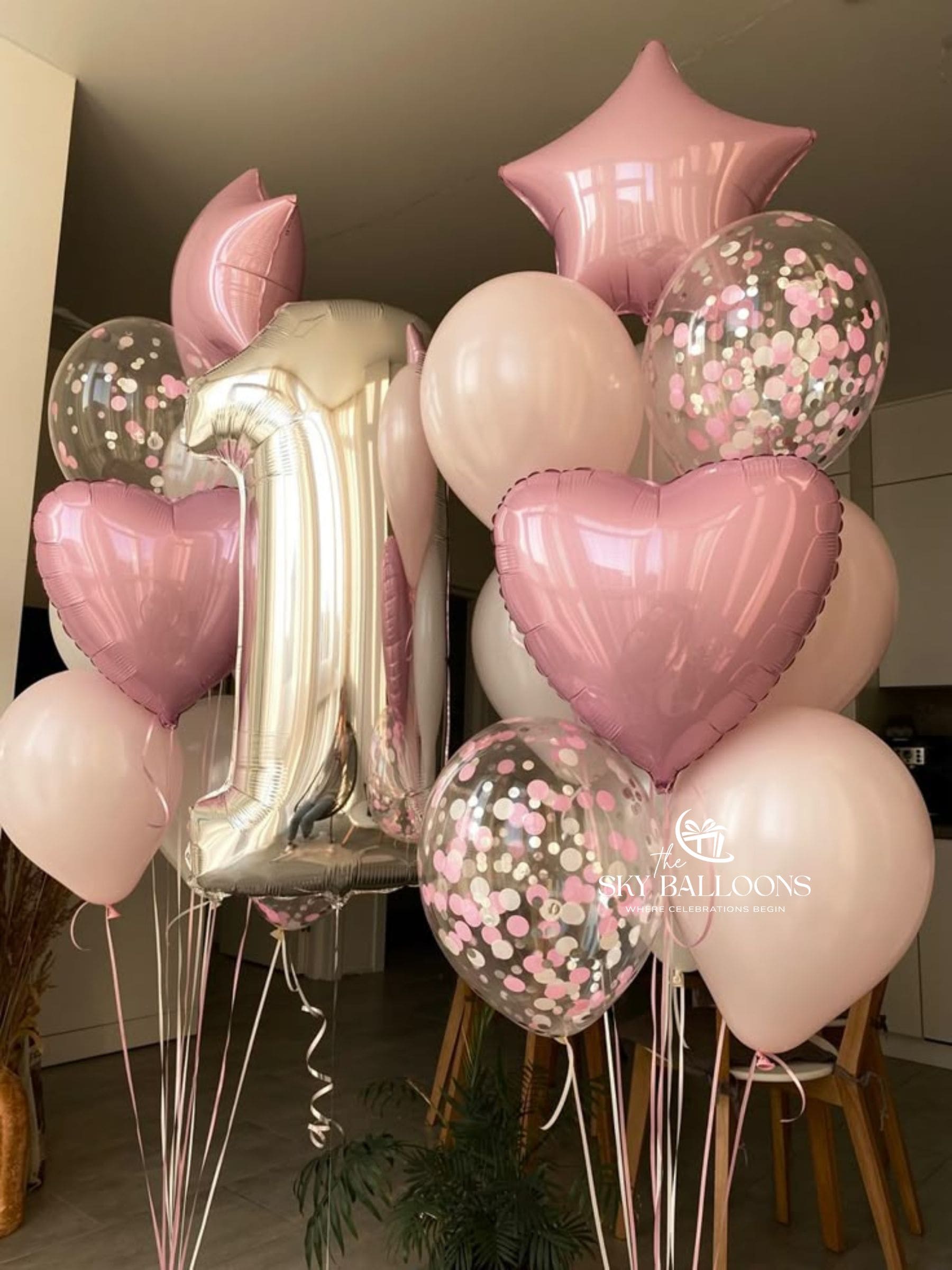 Silver number 1 foil balloon with two pastel pink balloon bouquets featuring pink hearts, stars and clear pink-confetti balloons.