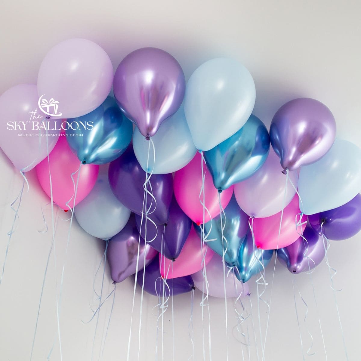 Purple, lilac, pink and pale-blue helium ceiling balloons with metallic purple and blue accents and hanging ribbons.
