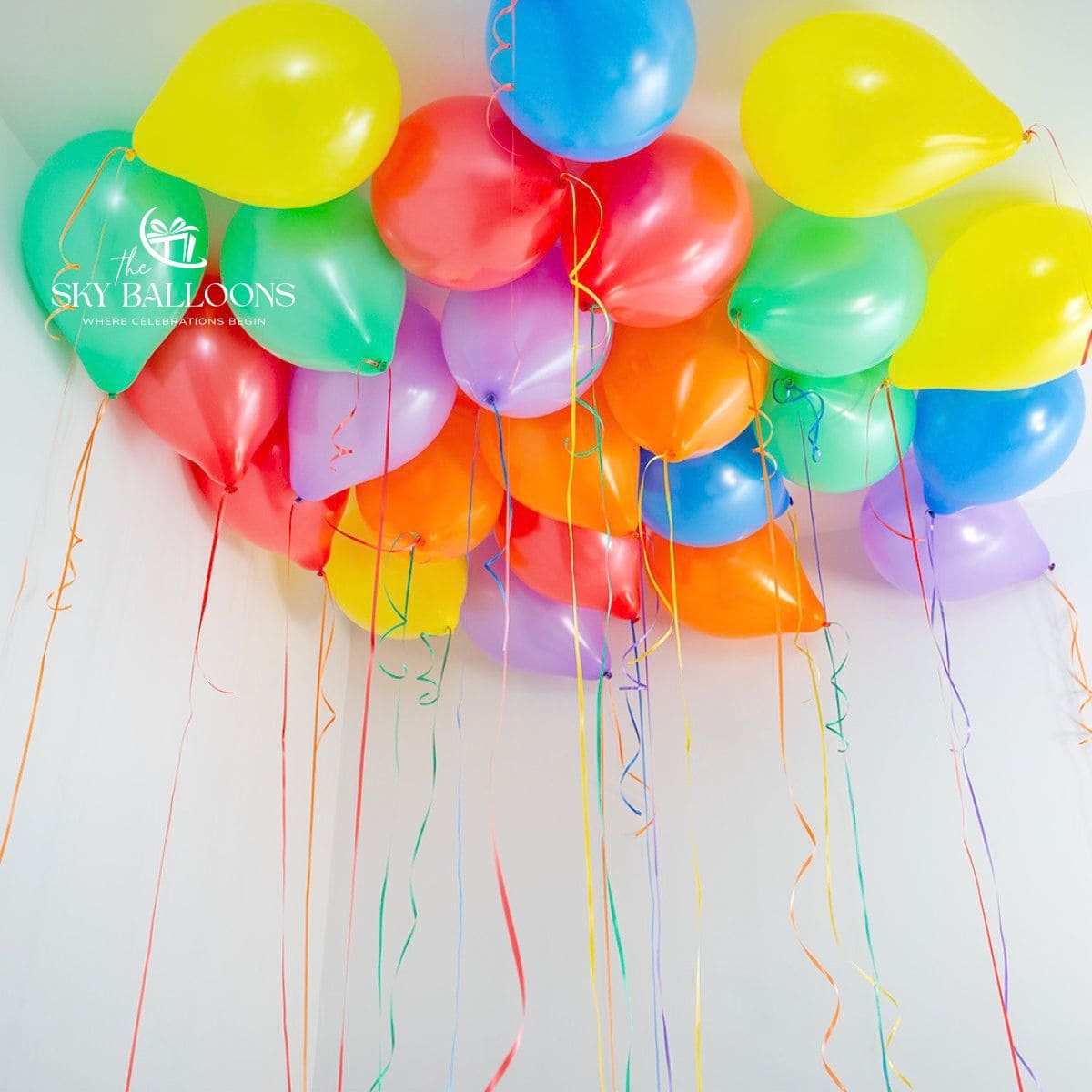Red, orange, yellow, green, blue and lilac helium ceiling balloons with multicoloured hanging curling ribbons.