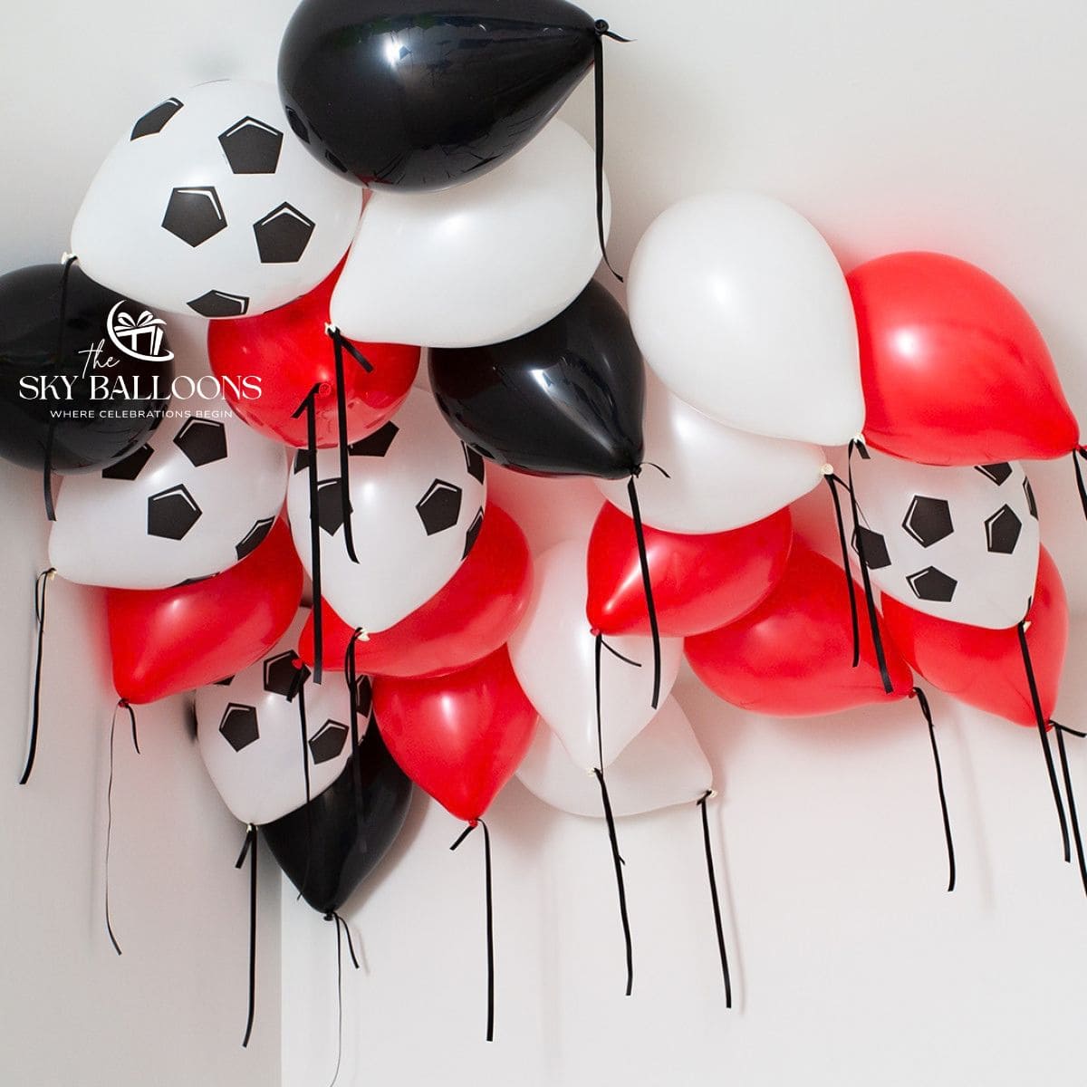 Red, black and white helium ceiling balloons with football-print balloons and hanging black ribbons.