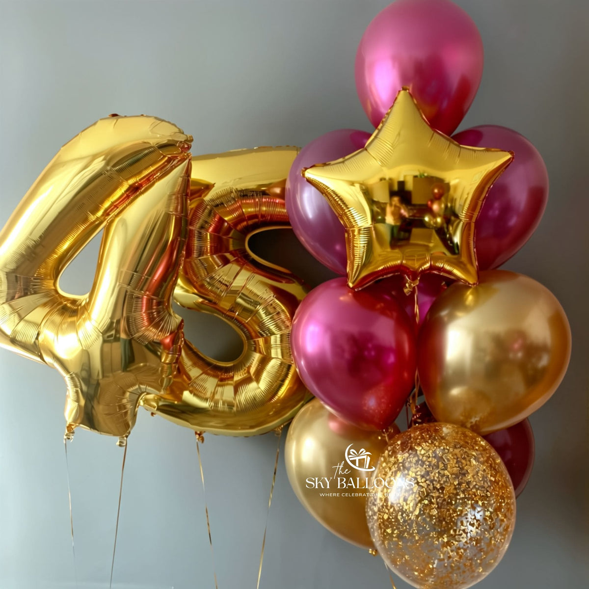 45th birthday balloon arrangement with gold number 45 and star foil balloons, metallic red and gold latex balloons, and a clear gold confetti balloon.