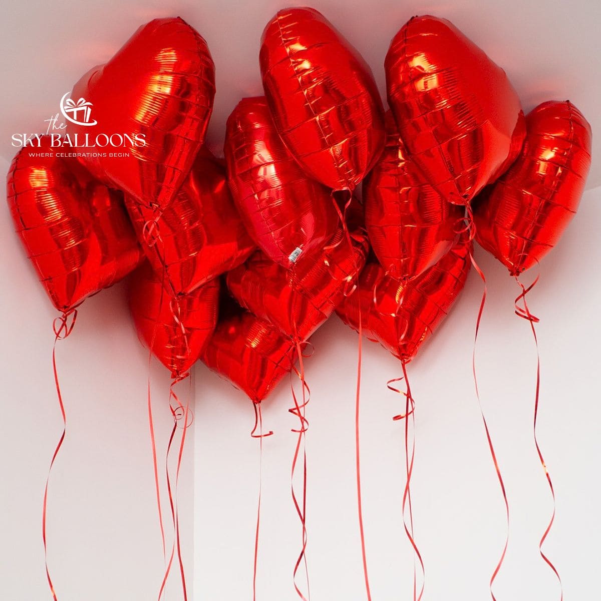 Red heart-shaped foil helium ceiling balloons with hanging red curling ribbons.