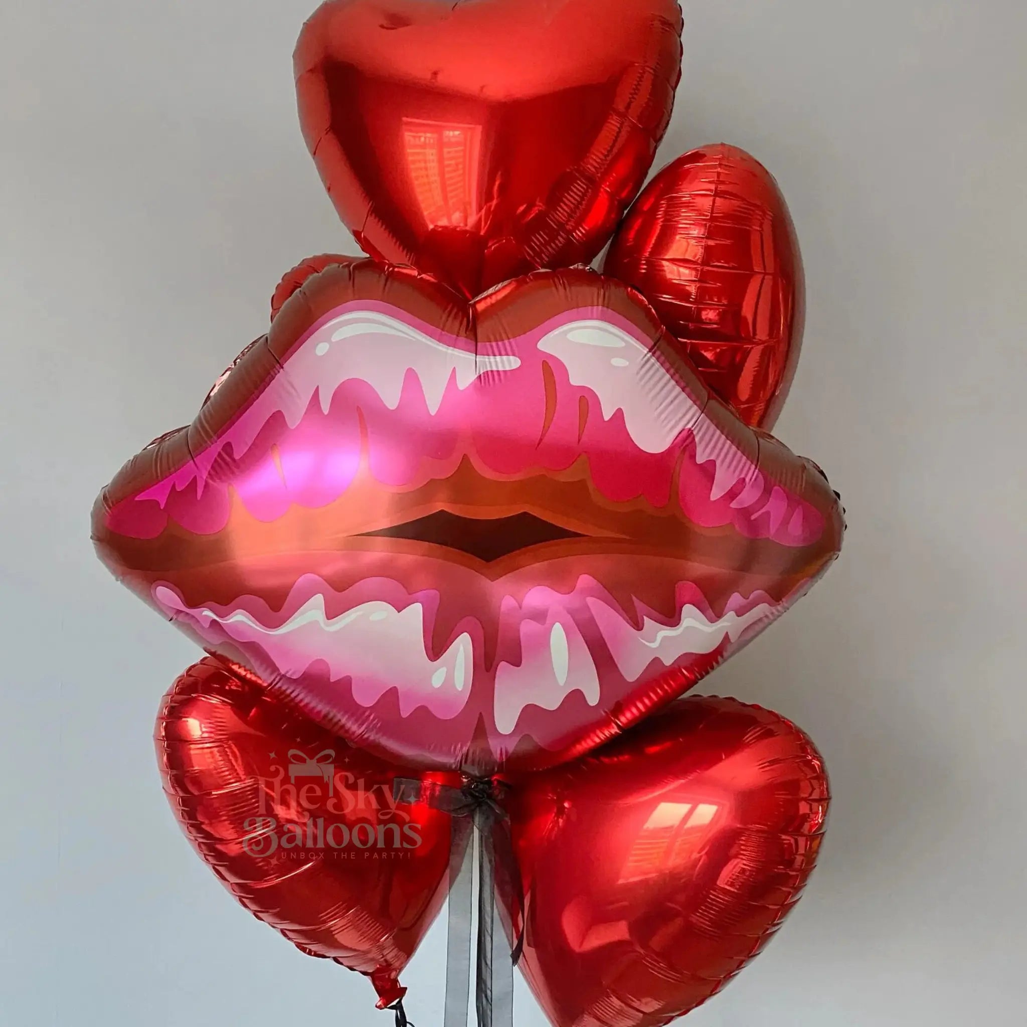 Red lip-shaped and heart-shaped balloons on a light gray background
