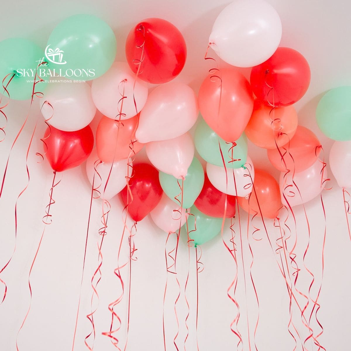 Red, mint-green, peach and white helium ceiling balloons with hanging red curling ribbons.