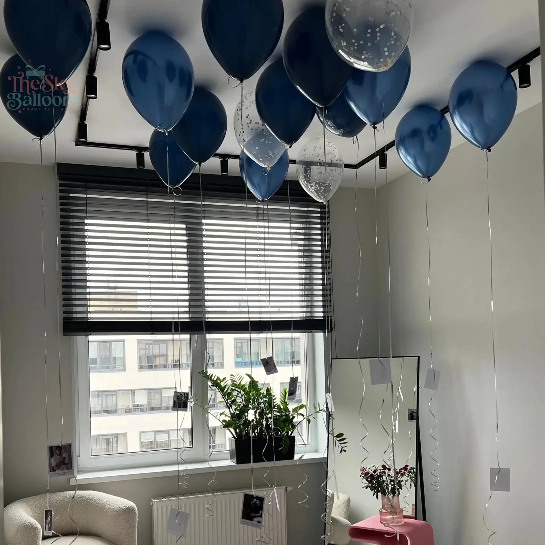 Room interior with blue and clear balloons, a window, and a plant.