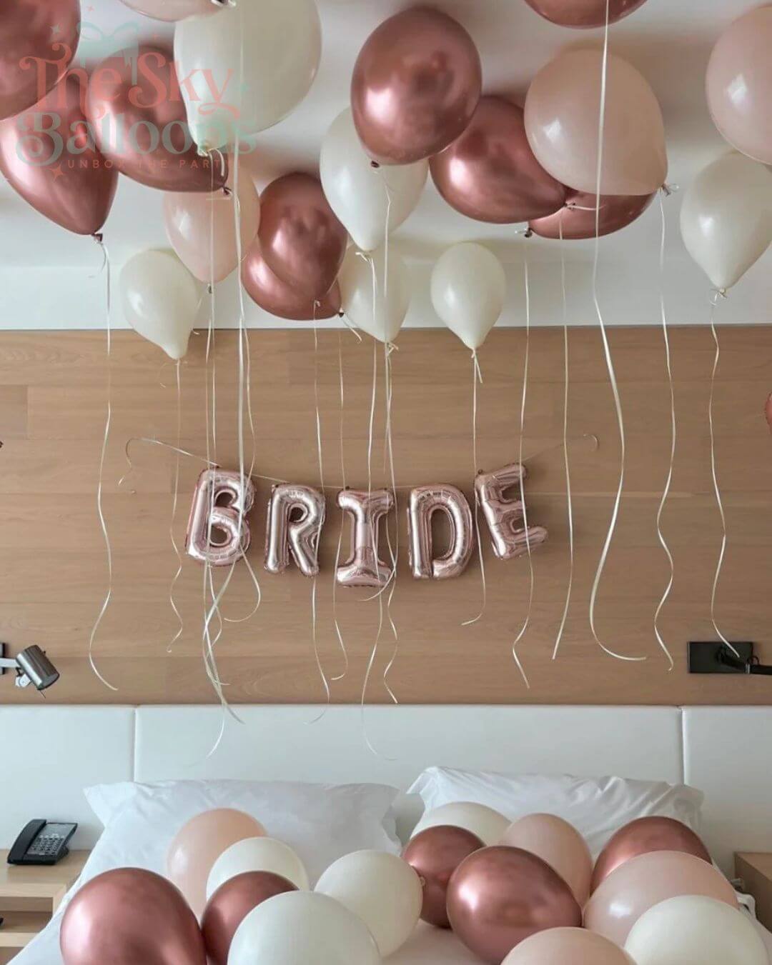 Balloon decoration with 'BRIDE' banner on a wooden surface.
