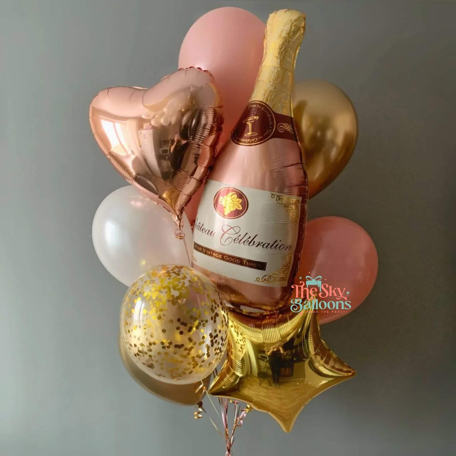 Bottle of champagne surrounded by balloons on a plain background