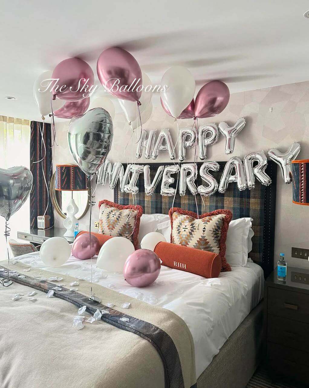 Decorated bedroom with 'Happy Anniversary' balloons and pillows.