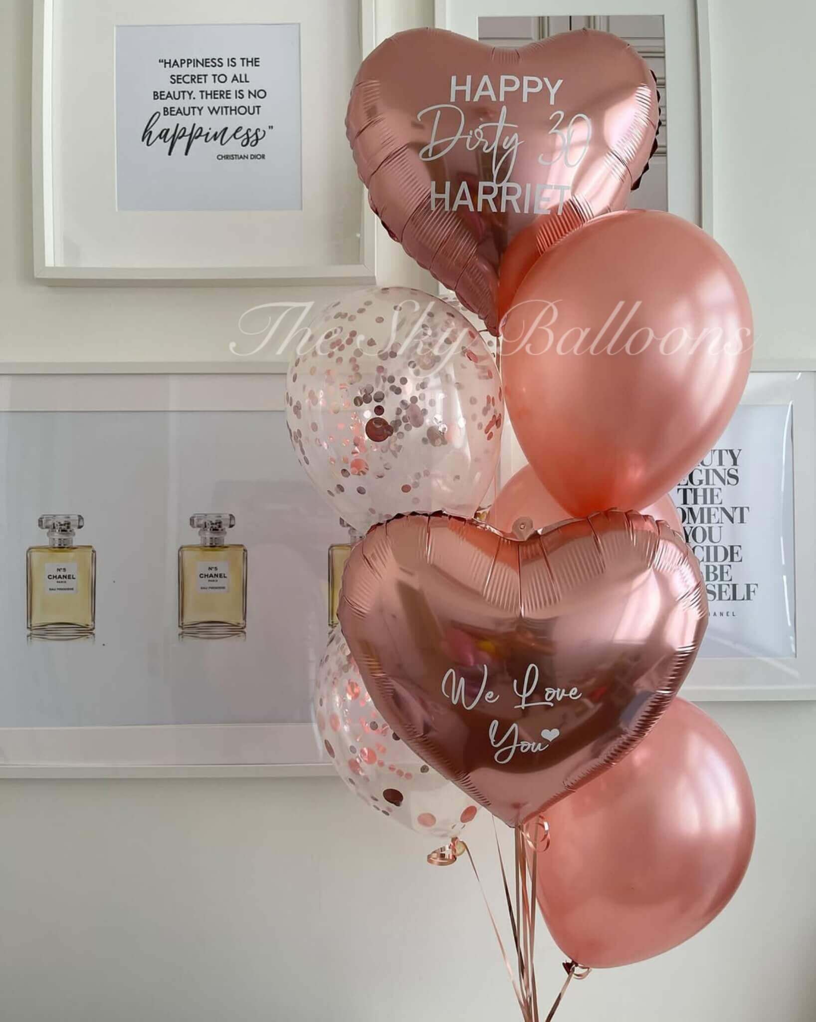 Rose gold balloons with personalized messages in a room setting.