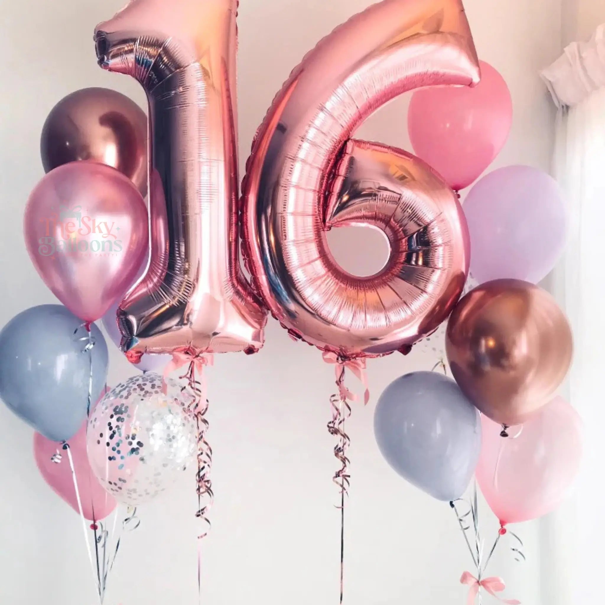 Rose gold number '16' balloons with other colorful balloons against a light background