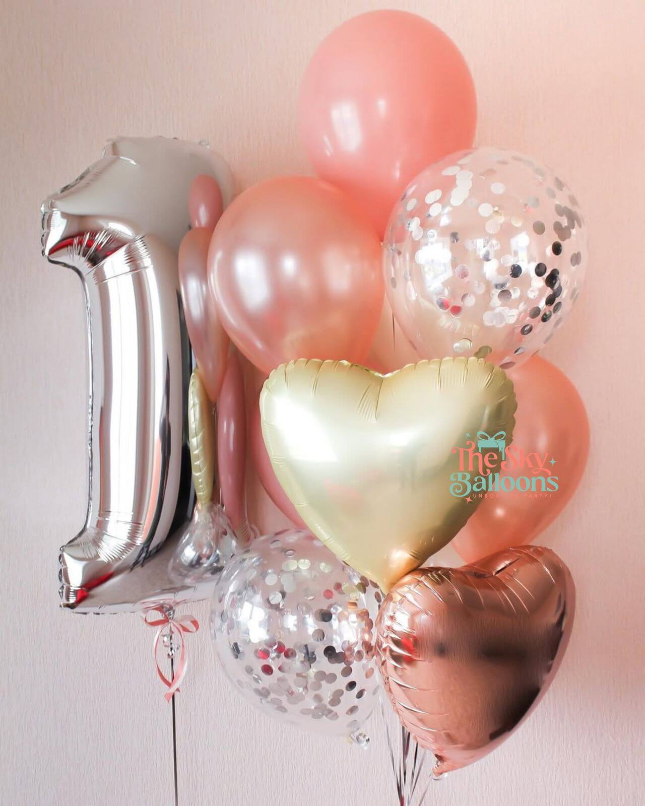 Silver number 1 balloon with pink and gold heart-shaped balloons on a light pink background