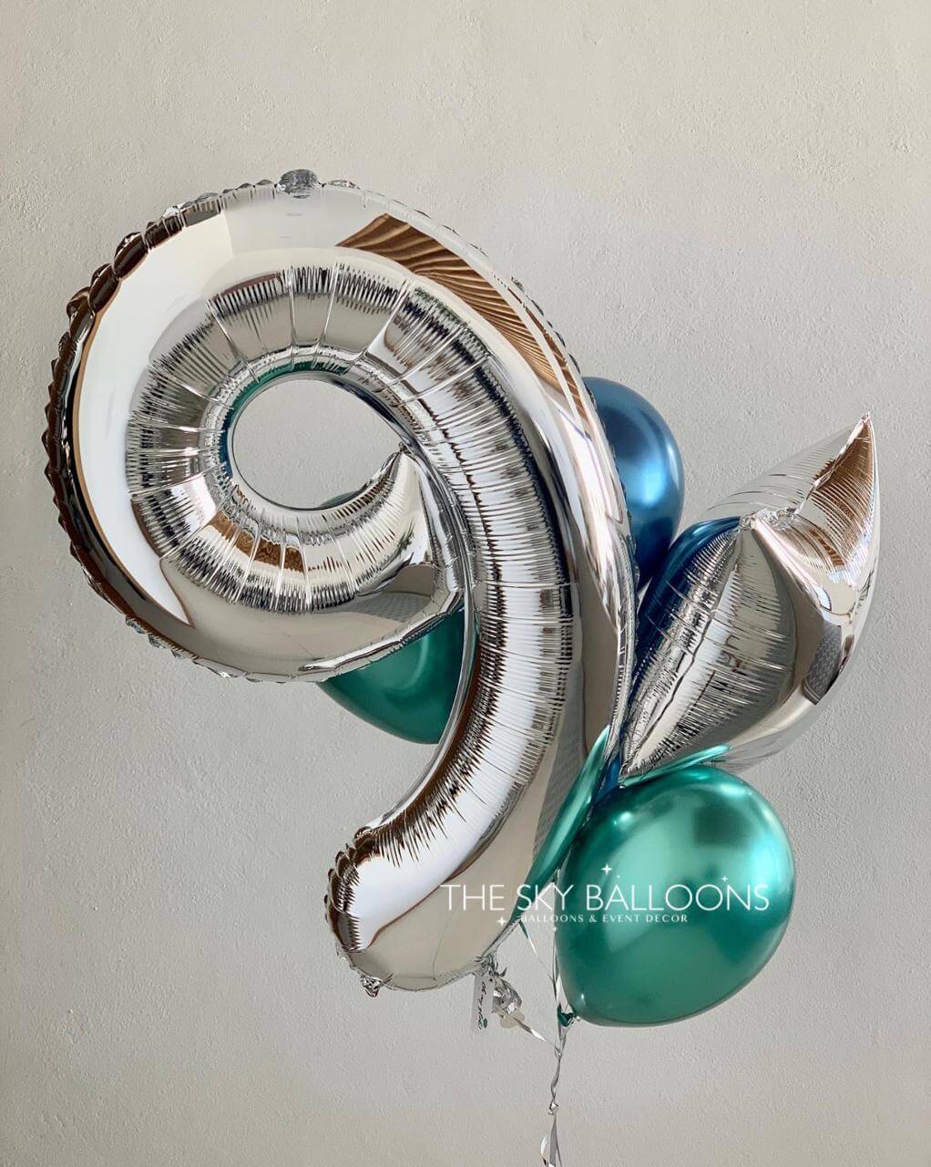 Silver and teal spiral balloon with 'The Sky Balloons' branding on a plain background