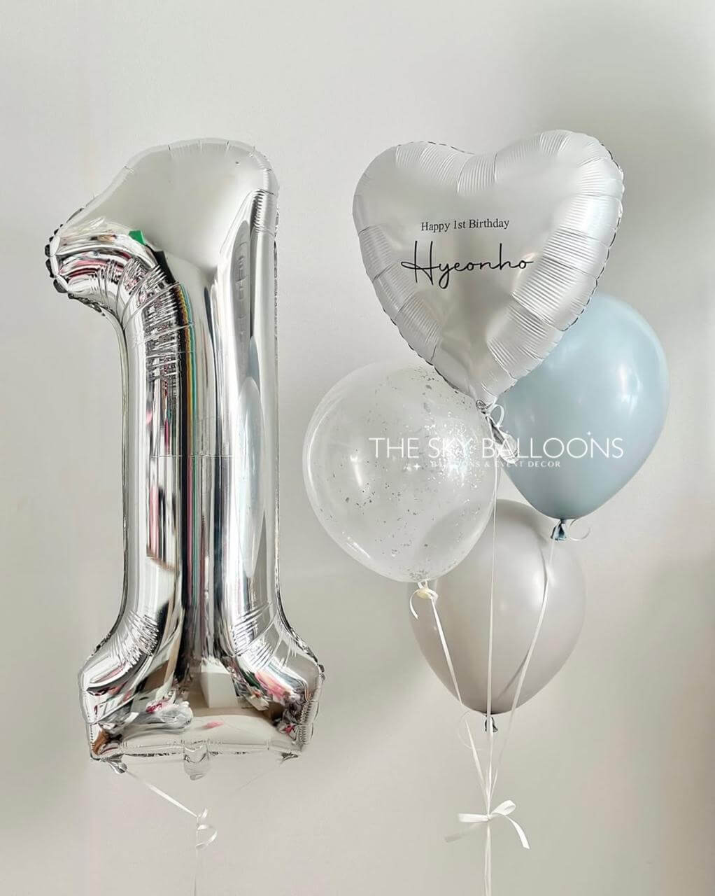 Silver number '1' balloon, heart-shaped balloon, and other balloons on a light gray background.